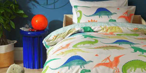 A Habitat kids dino multicolour bedding set on a bed.